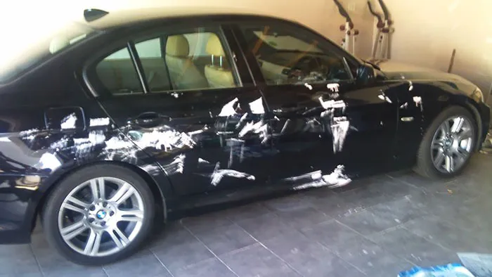 Car covered in white paint smudges in a garage, illustrating the chaos when kids are left alone.