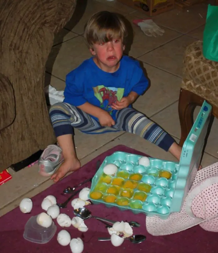 Child upset on the floor with broken eggs and spoons scattered around, illustrating hilarious kid mishaps.