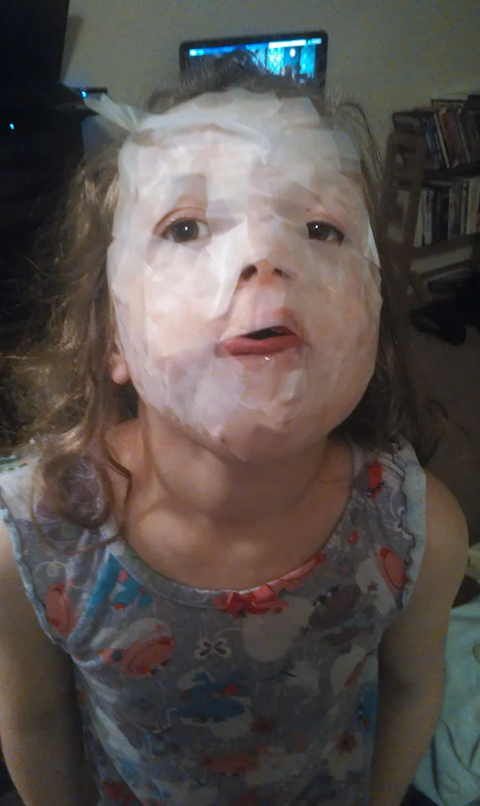 Child covered in translucent tape for playful mischief, showing the hilarious side of being left alone.