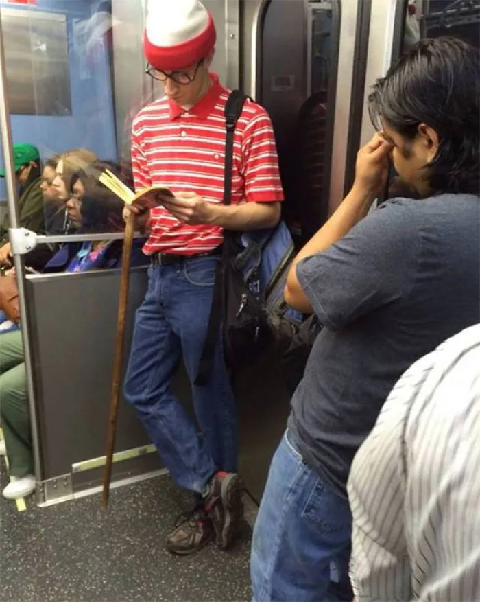 Person dressed in red and white stripes reading on subway, exemplifying weirdest subway rider attire.