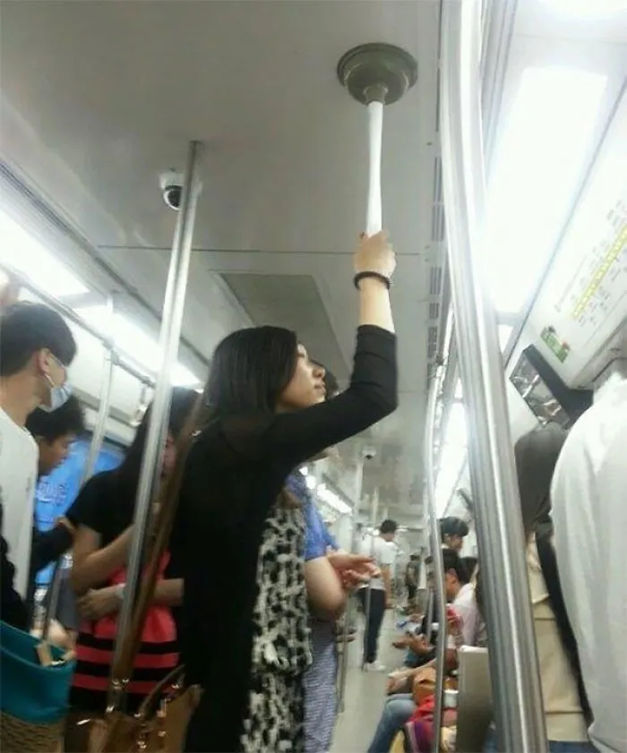 Woman holding a subway ceiling with a plunger, showcasing weird subway moments.