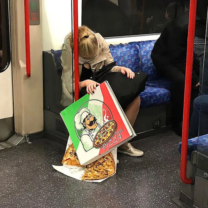 Subway passenger with a giant pizza box, slices spilling onto the floor.