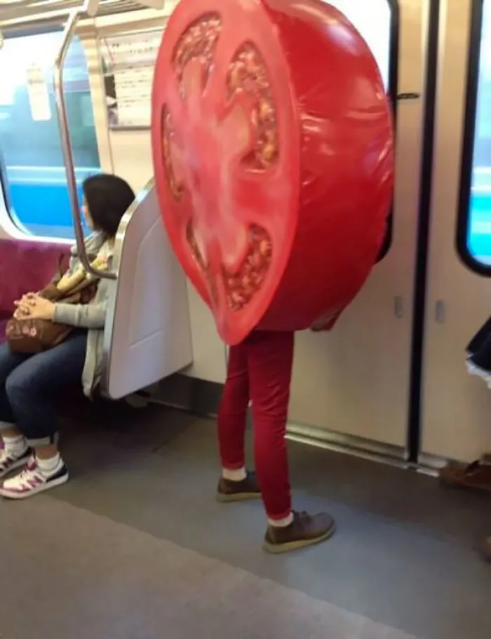 Person in tomato costume riding the subway, capturing weirdest moments underground.