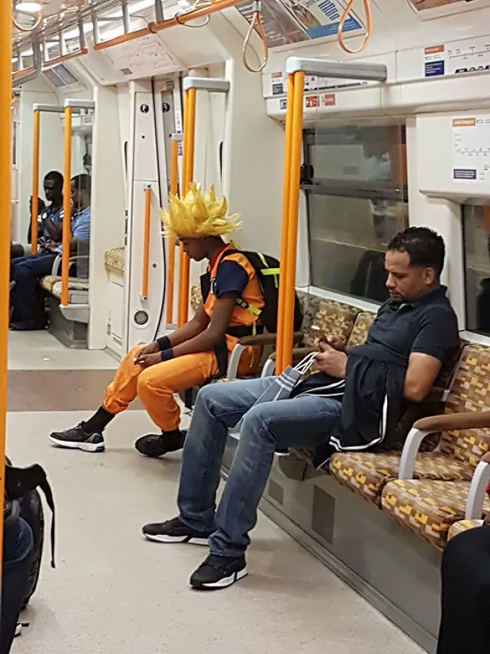 Person in a vibrant costume seated on a subway train.