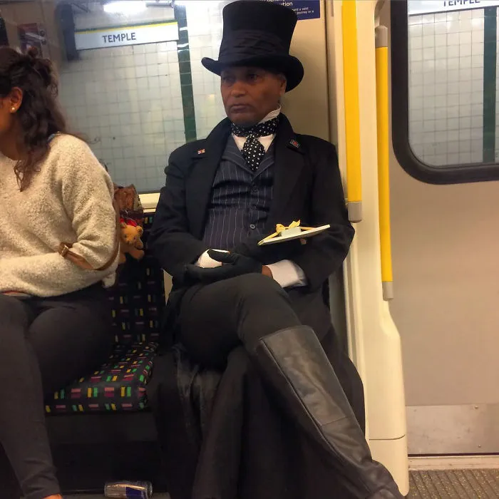 Man in Victorian attire on subway, wearing a top hat and holding a plate.