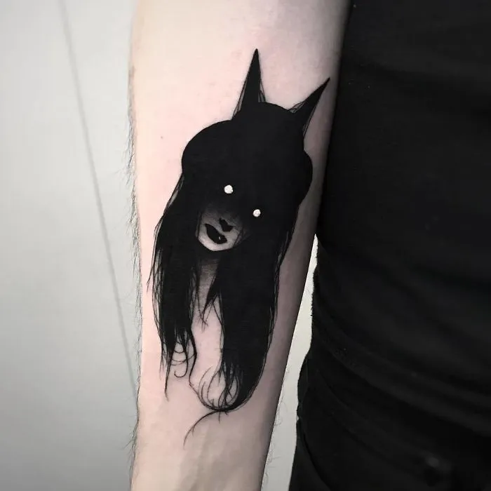 Tattoo of a faceless girl with long hair on an arm, in a slightly erotic and mysterious design.