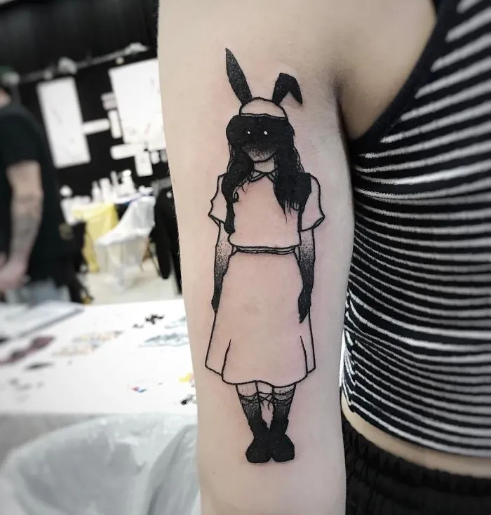 Tattoo of a faceless girl with bunny ears on a person's arm, featuring a slightly erotic and mysterious design.