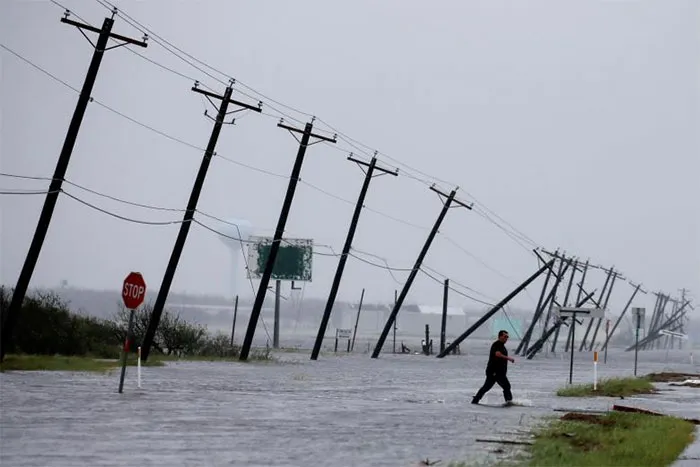 A Man Walks Through Floodwaters And Onto The Main Road After Surveying His Property