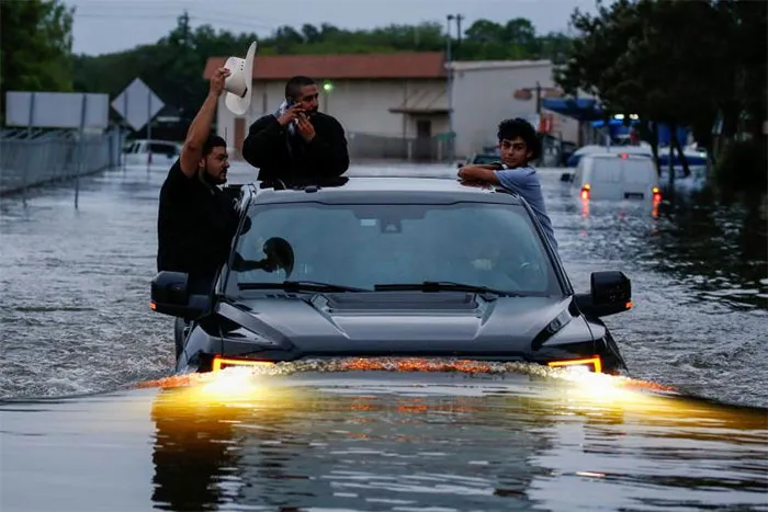 Residents Use A Truck To Navigate Through Flood Waters In Houston