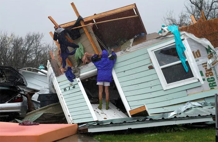 A Woman Uses A Coat Hanger To Try And Retrieve An Item From A Destroyed House In Fulton
