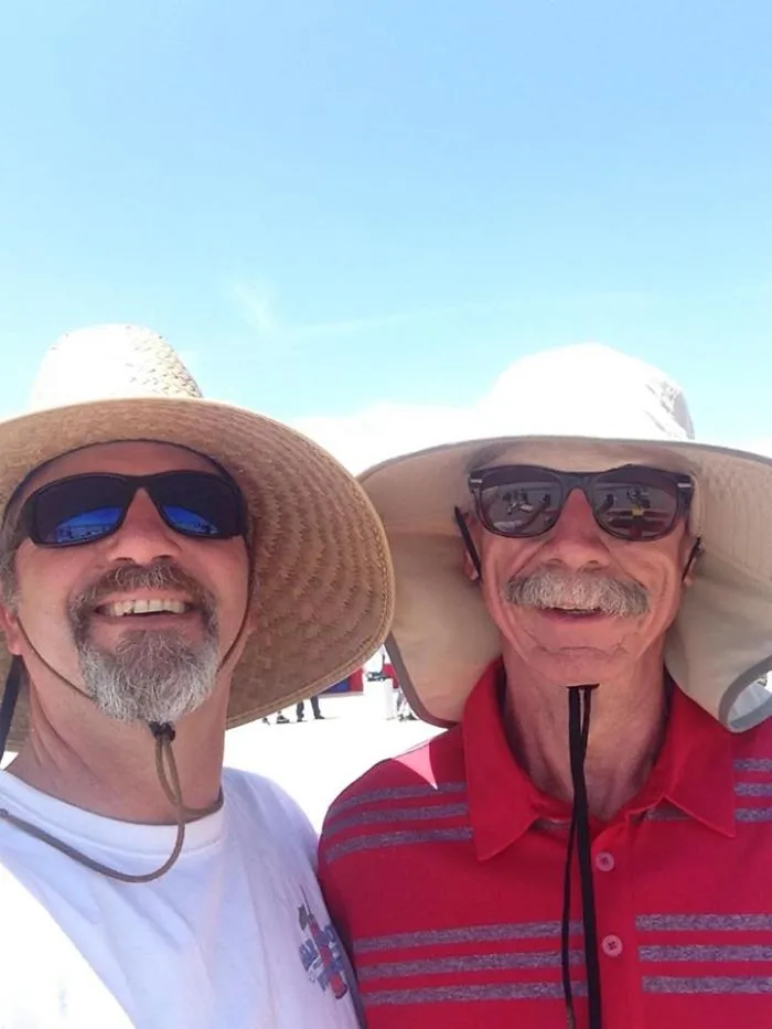Two smiling men in sun hats and sunglasses, illustrating depression symptoms have no face.