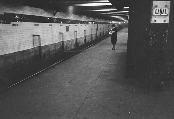 1940s New York subway station, lone figure holding a newspaper, captured by Stanley Kubrick.