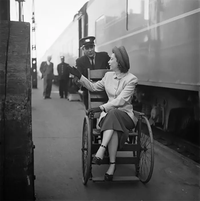 1940s New York train scene with a woman in a wheelchair talking to a conductor. Photo by young Stanley Kubrick.