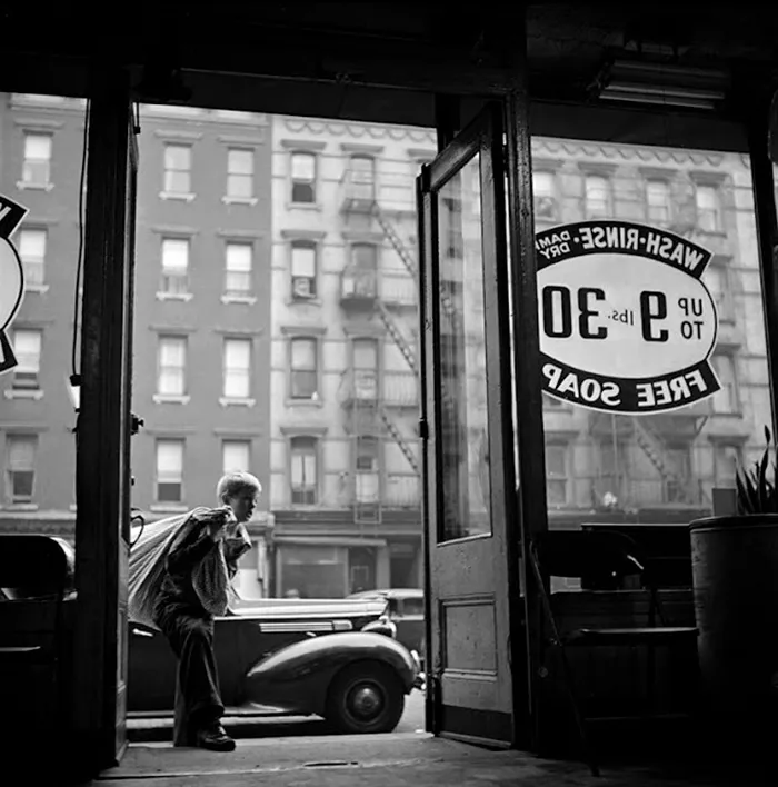 17-year-old's photo of 1940s New York, capturing a boy on a street through a laundromat door.