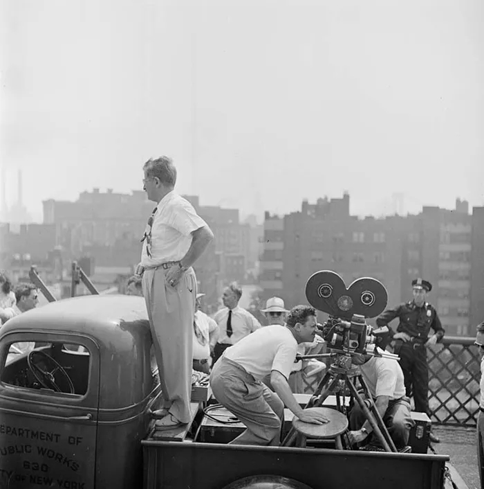 Black and white photo of a 1940s New York city scene with film crew working on a truck, capturing urban life.