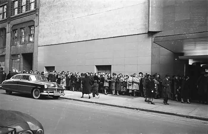 Crowd in 1940s New York captured by 17-year-old Stanley Kubrick, showcasing urban life and vintage cars.