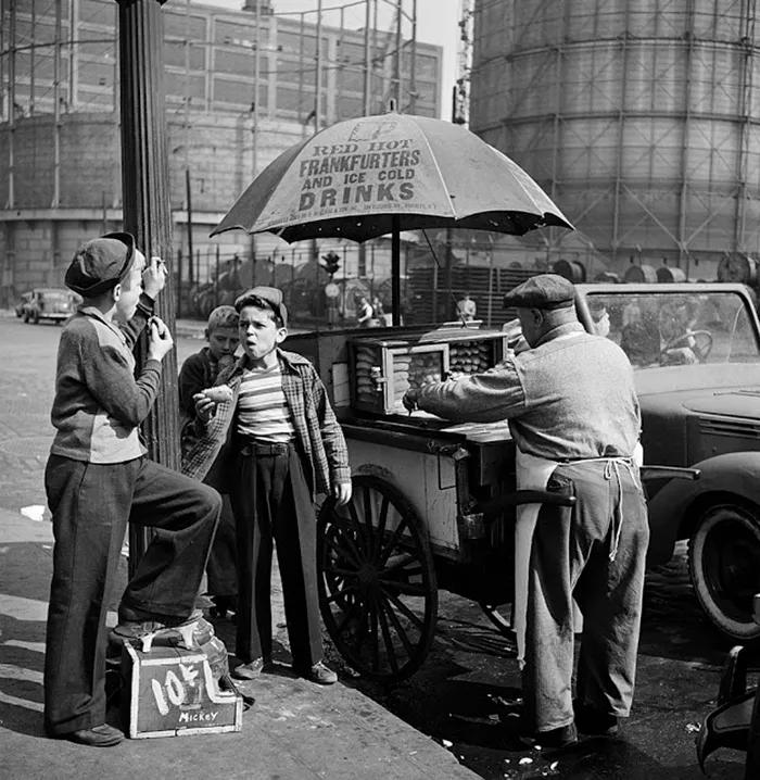 1940s New York street scene with boys eating at a hot dog stand, showcasing Kubrick's early photographic talent.
