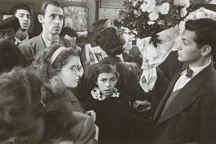 Crowded 1940s New York subway scene captured by young Stanley Kubrick, featuring a man with flowers.