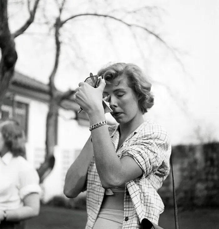 Young woman applying makeup outdoors, captured in 1940s New York by 17-year-old photographer Stanley Kubrick.