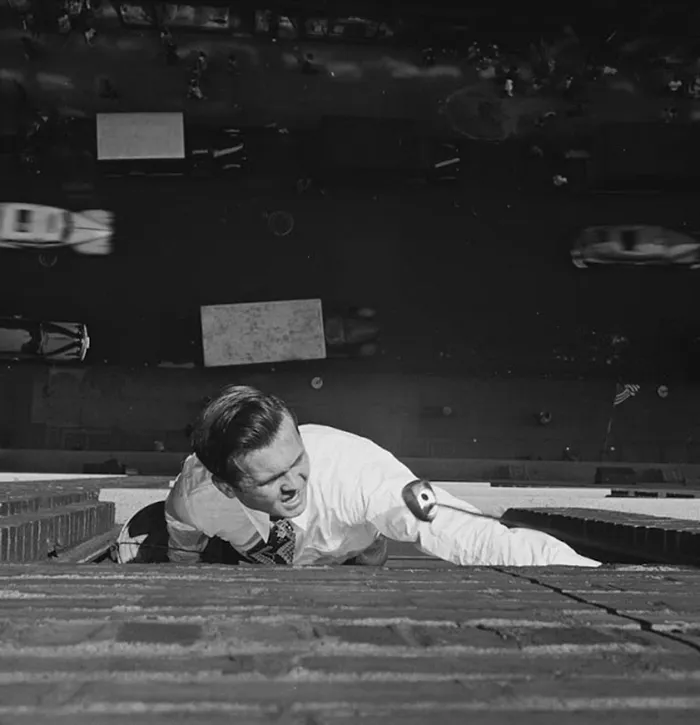 Man climbing building, 1940s New York street below, showcasing young Stanley Kubrick's genius in photography.