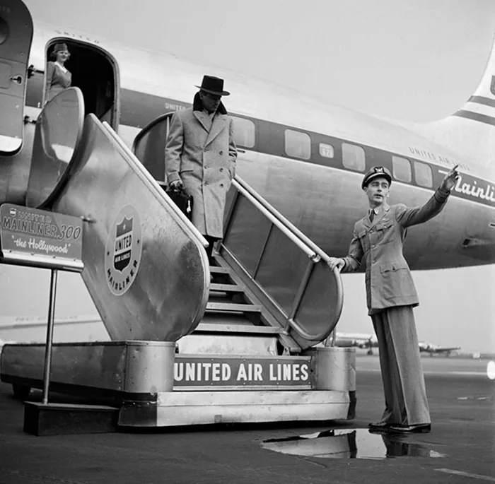 1940s New York photo by Stanley Kubrick showing a man in a coat descending plane stairs, with United Air Lines branding.