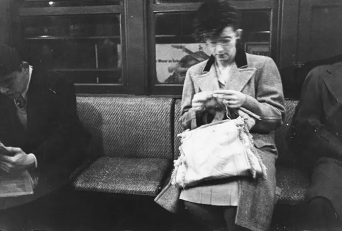1940s New York subway scene, photographed by Stanley Kubrick, captures a woman in a coat knitting next to two men.