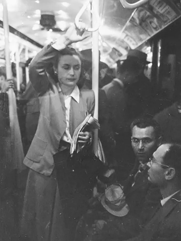 1940s New York subway scene captured by Stanley Kubrick, featuring a woman standing and two men seated.