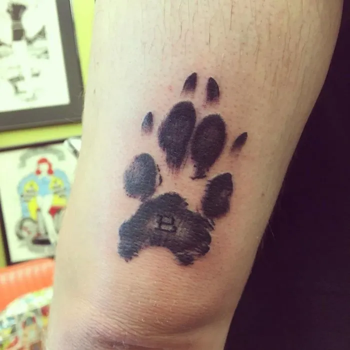 Tattoo of a dog paw print on an arm, highlighting the pawesome design in a tattoo studio setting.