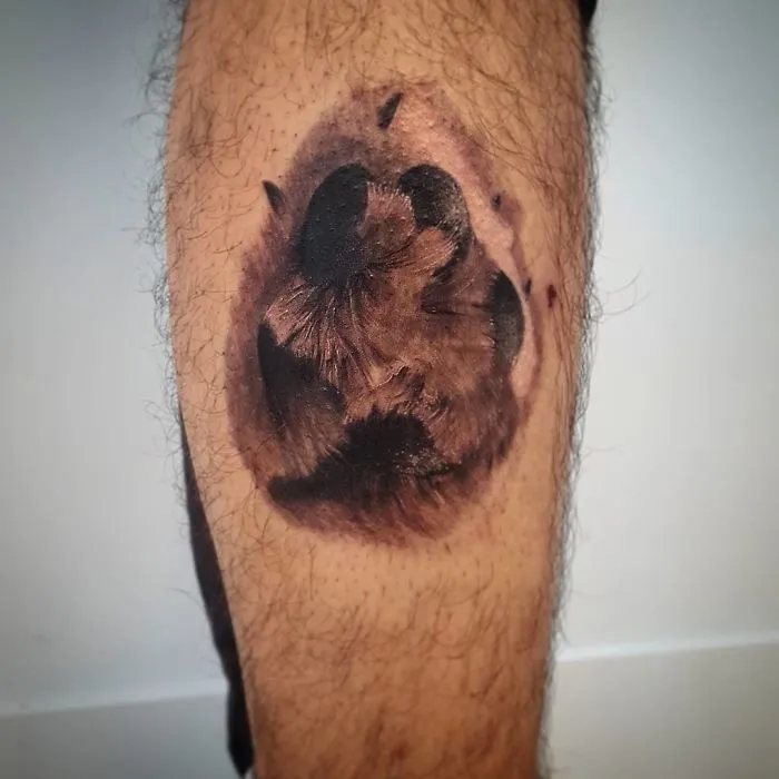 Dog paw print tattoo on a leg, showcasing artistic ink design.