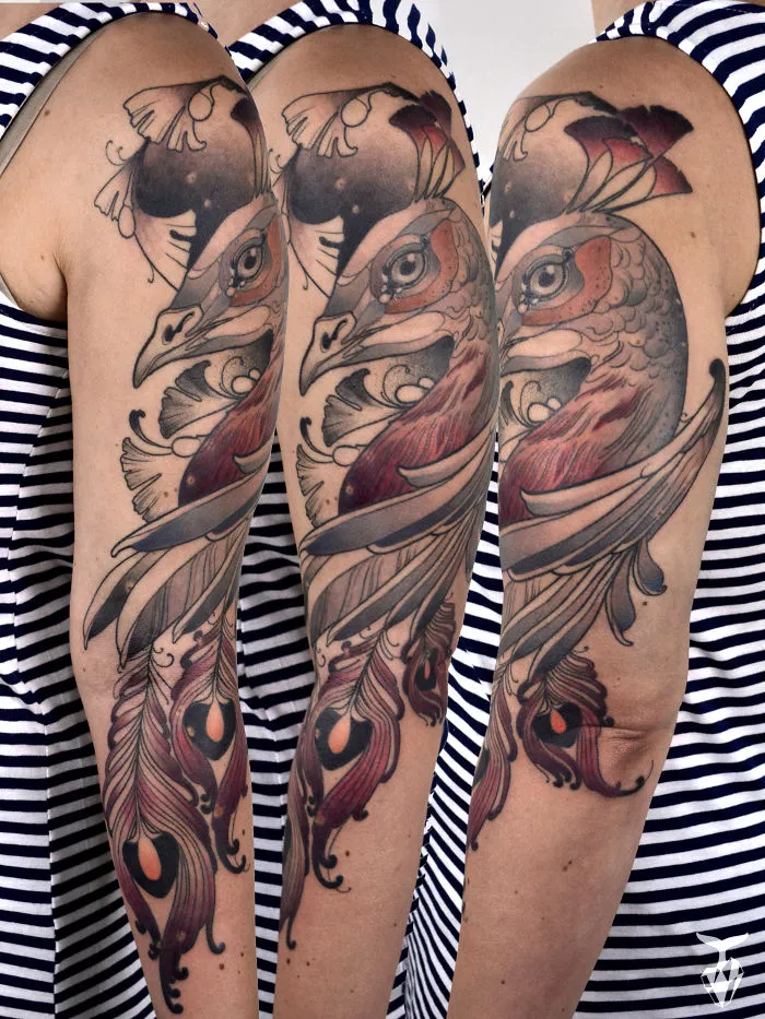 Nature art nouveau inspired tattoo featuring a detailed bird and feather design on an arm, against a striped shirt background.