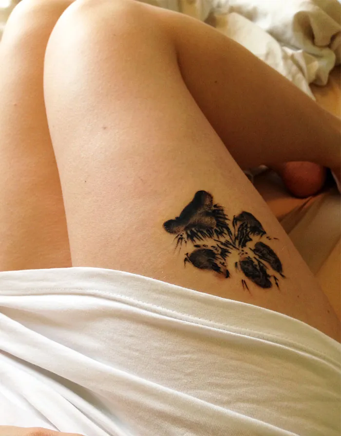 Dog paw print tattoo on thigh, showcasing intricate design.