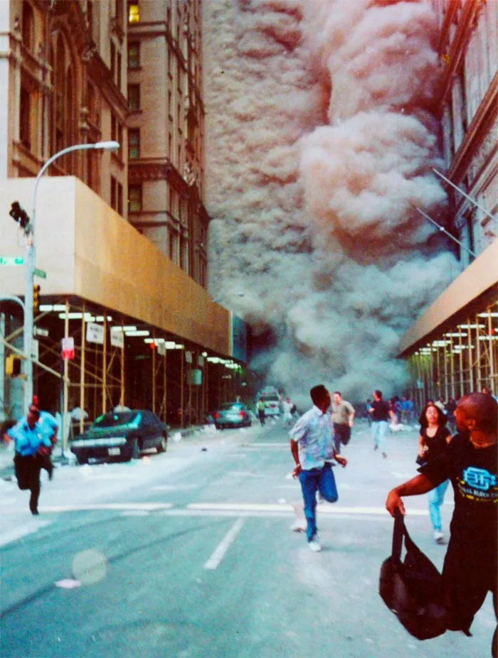 Gente corriendo por Broadway huyendo de la nube de humo y polvo tras caer una torre