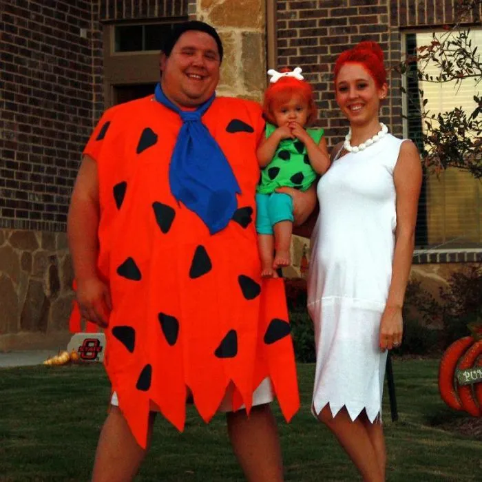 Family dressed in retro Flintstones theme Halloween costumes smiling outdoors