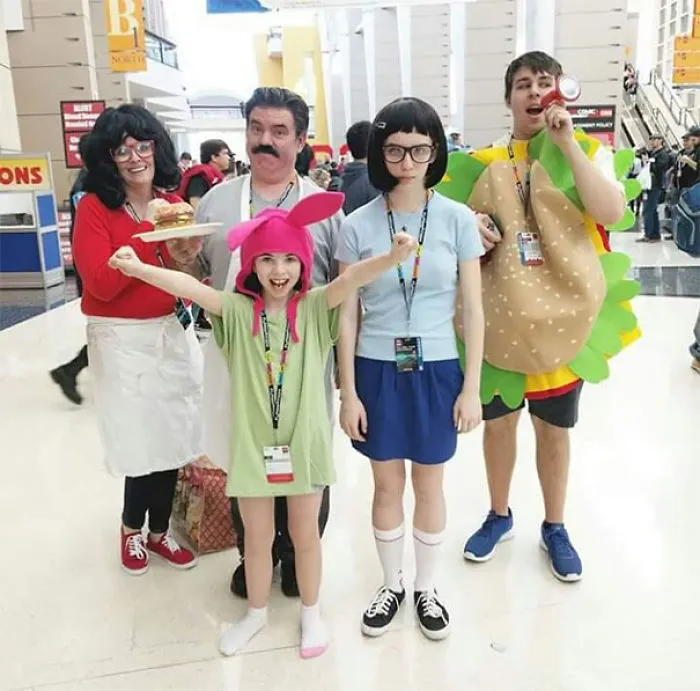 A family posing in creative Bob's Burgers family Halloween costumes at a convention event.