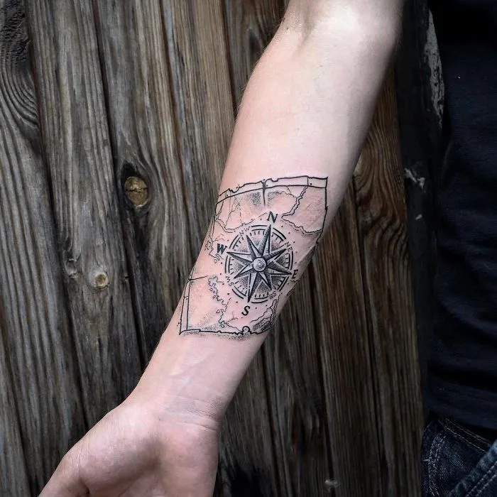 Compass travel tattoo on forearm with map design, inspiring wanderlust and adventure.