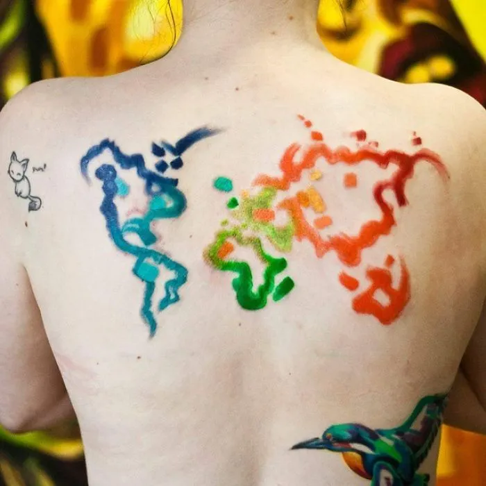 Colorful world map tattoo on a person's back, inspiring travel ideas.
