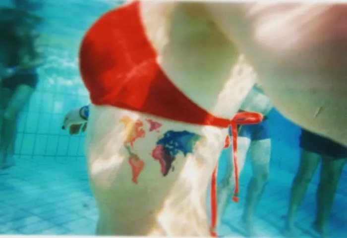 Underwater view of a world map tattoo on a thigh, embodying travel inspiration.