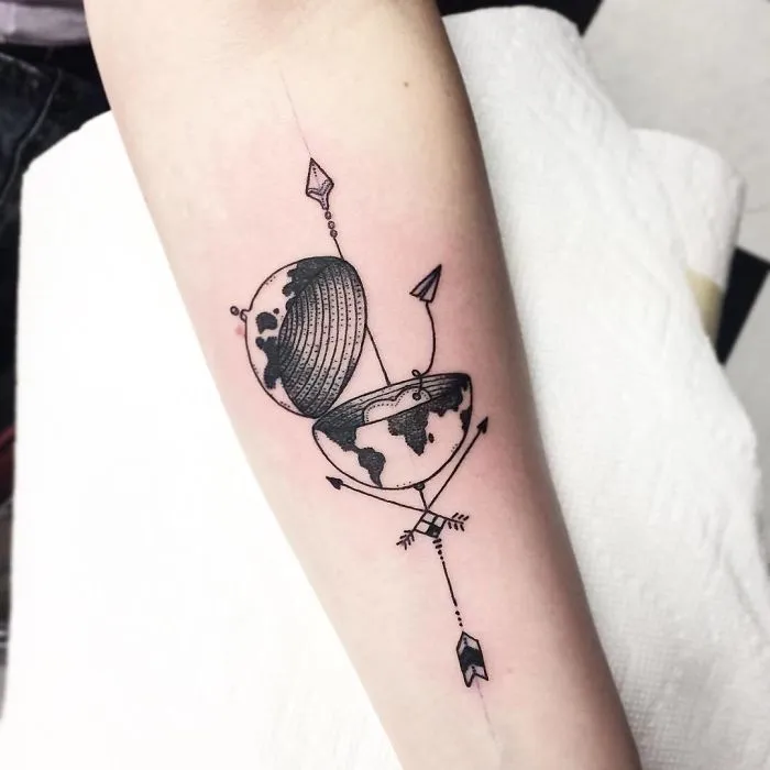 Travel tattoo of a split globe with arrows on a forearm, inspiring wanderlust.