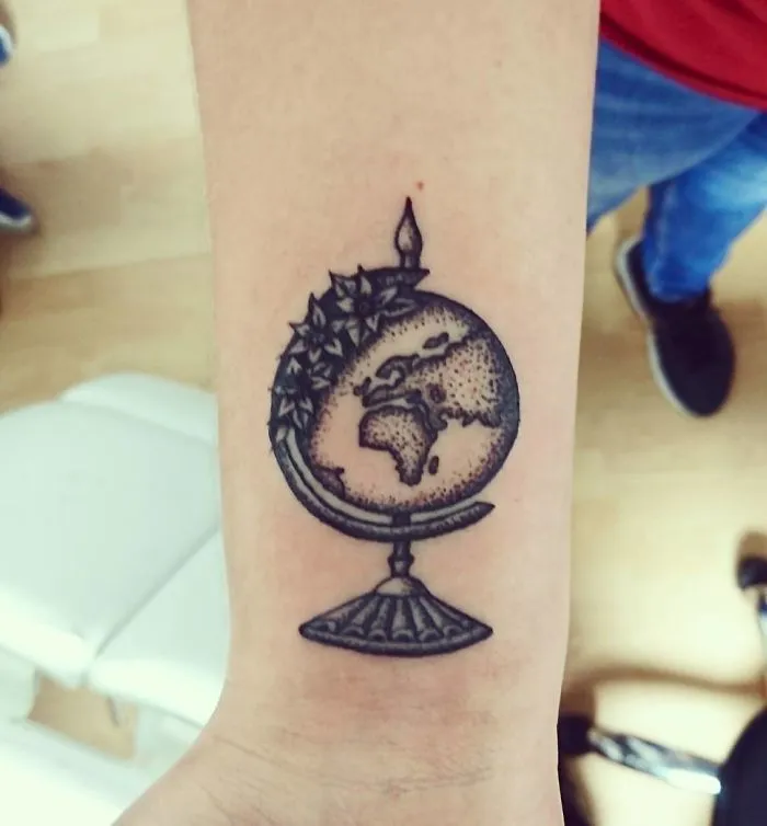 Travel tattoo of a detailed globe on an arm, featuring continents and stars, inspiring wanderlust and adventure.
