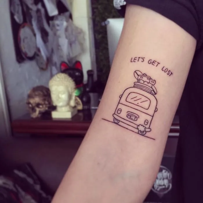 Travel tattoo of a camper van with "Let's Get Lost" on an arm, inspiring wanderlust and adventure.