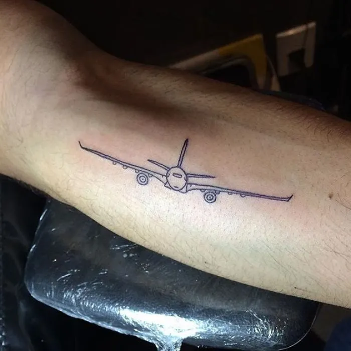 Airplane tattoo on arm, representing travel inspiration.