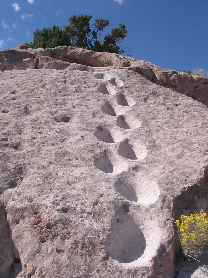 Huellas de excursionistas en la roca volcánica de Tsankawi
