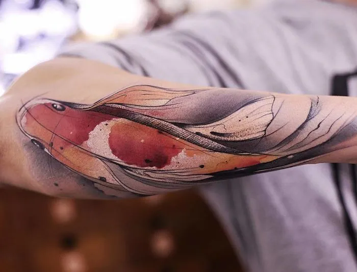 Watercolor tattoo by Chen Jie on an arm, featuring vibrant, flowing designs and colors.