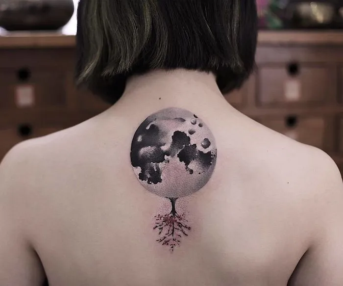 Watercolor tattoo of a moon with roots on a person's back, designed by Chen Jie.
