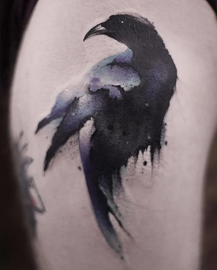 Watercolor tattoo of a raven with purple and black hues on skin.