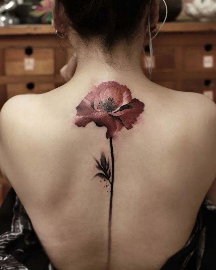 Watercolor tattoo by Chen Jie featuring a red poppy design on a person's back.