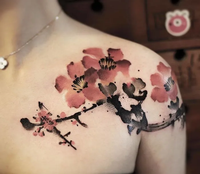 Watercolor tattoo of cherry blossoms on shoulder, featuring vibrant pinks and blacks.