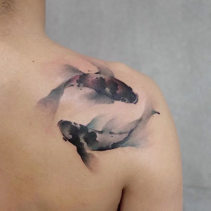 Watercolor tattoo of koi fish on a person's shoulder, demonstrating Chen Jie's artistic technique.