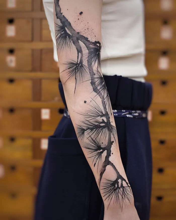 Watercolor tattoo on an arm by Chen Jie, featuring abstract black ink brushstroke design.