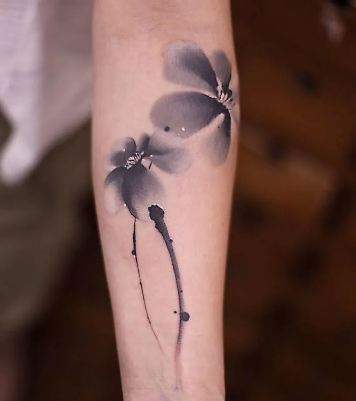 Watercolor tattoo of abstract flowers on an arm, showcasing Chen Jie's artistic style.